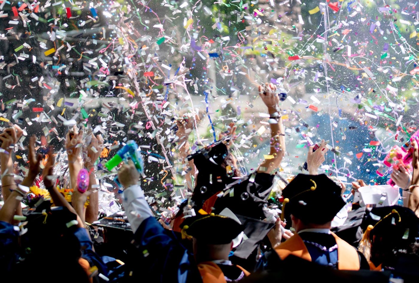 Students celebrating at graduation, throwing caps amid confetti